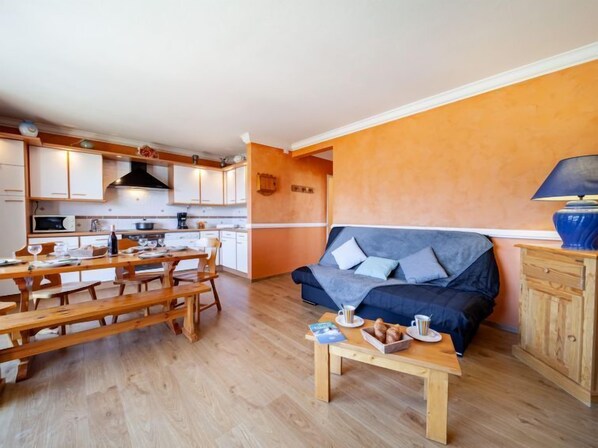 Een gezellig, compact verblijf met een kitchenette, een eethoek en een zithoek met een bank en salontafel.