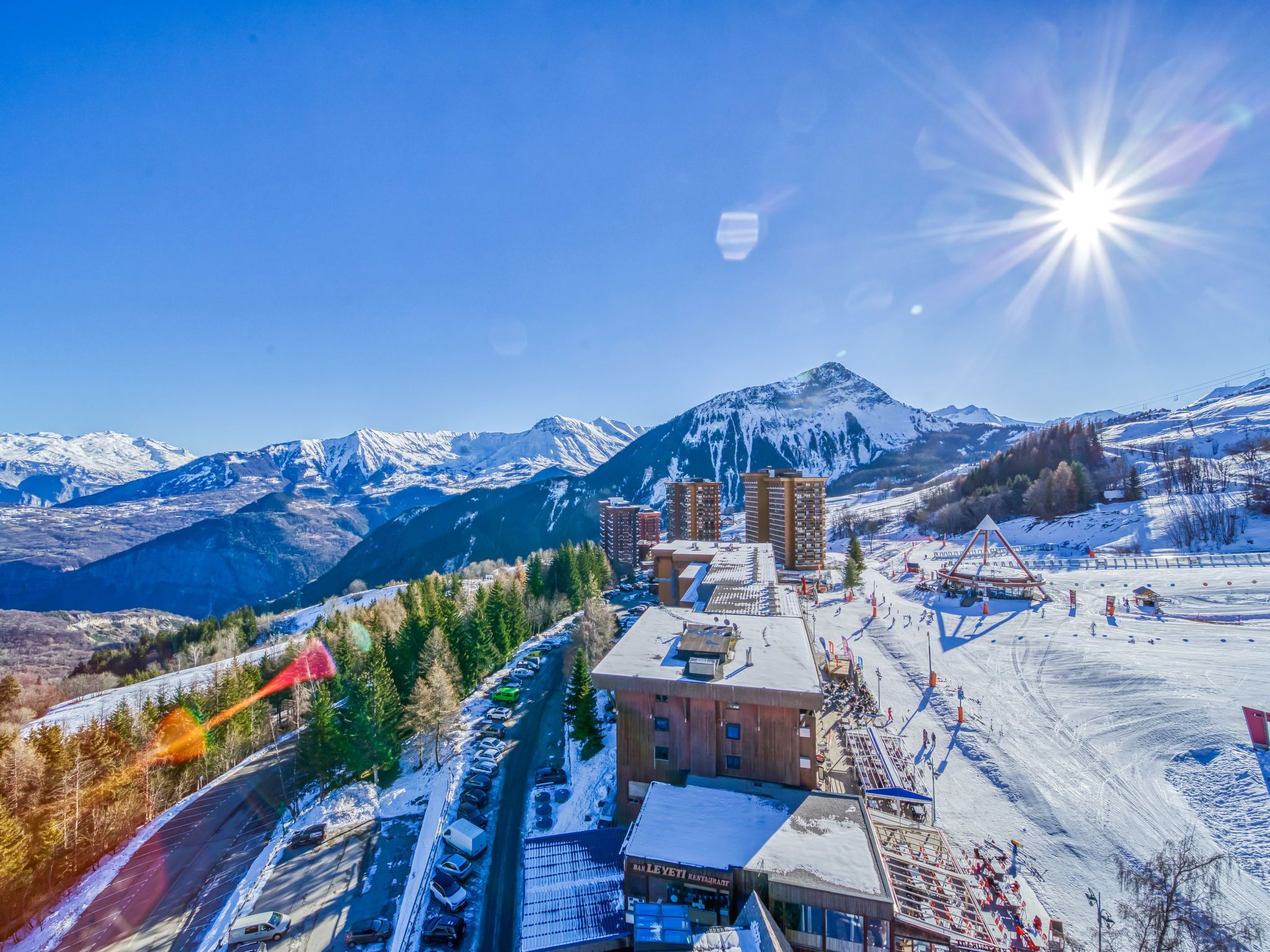 A hotel with a ski slope in the background, surrounded by mountains.