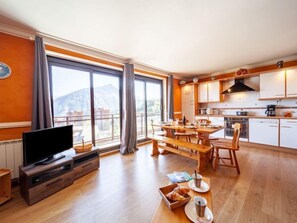 Een moderne woonkamer met een televisie, eethoek en keuken.