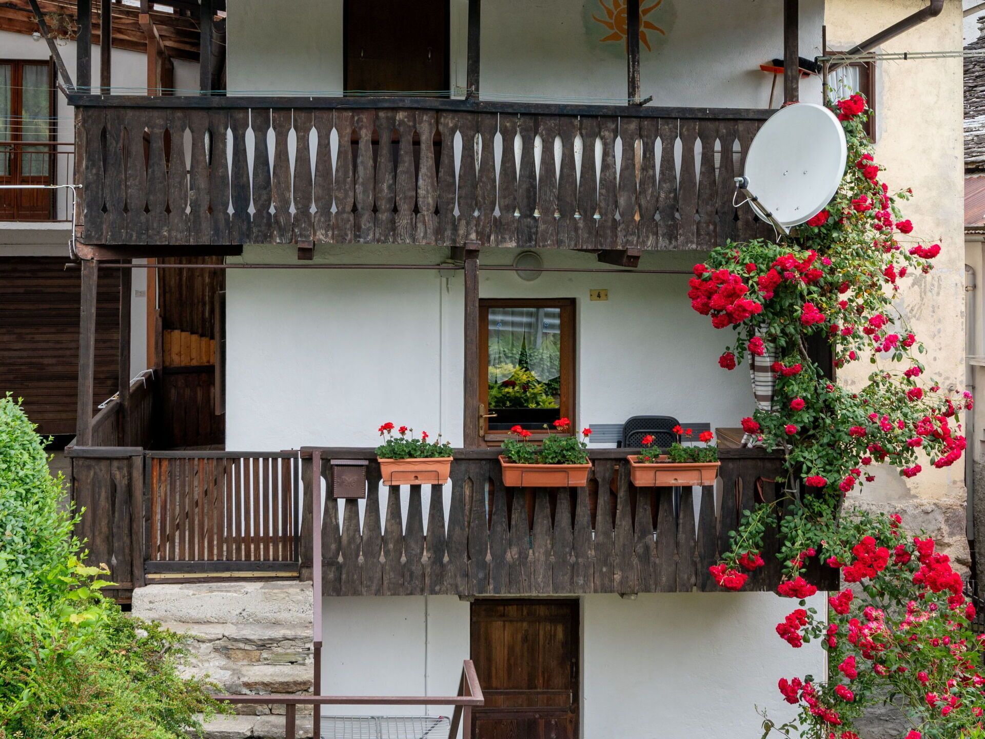 Un chalet traditionnel doté d’un balcon en bois, de plantes en pot et d’une antenne parabolique.