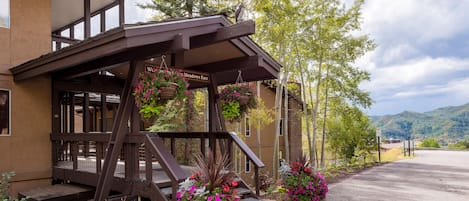 Step into a charming hotel entrance with a beautiful wooden staircase and vibrant flower baskets.