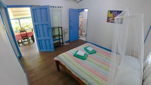 A room with a bed, a fan, a table with chairs, and a door leading outside. - Private Villa, front yard (Punta Uva)