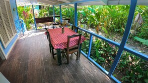 A covered patio with a wooden table and chairs, surrounded by lush greenery. - Private Villa, front yard (Punta Uva)