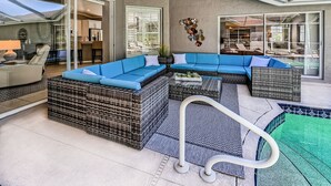 A modern outdoor living area with a large sectional sofa, wicker furniture, and a pool. - Naples- Briarwood Estates all new 4BR/3 BA, sleeps 10, vacation rental (Naples)