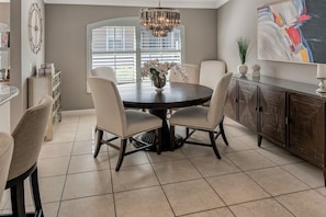 Enjoy meals in this cozy dining area with a round table and four chairs, surrounded by a vase with fresh flowers.