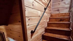 Een houten trap met een leuning, leidend naar een hoger gelegen verdieping.