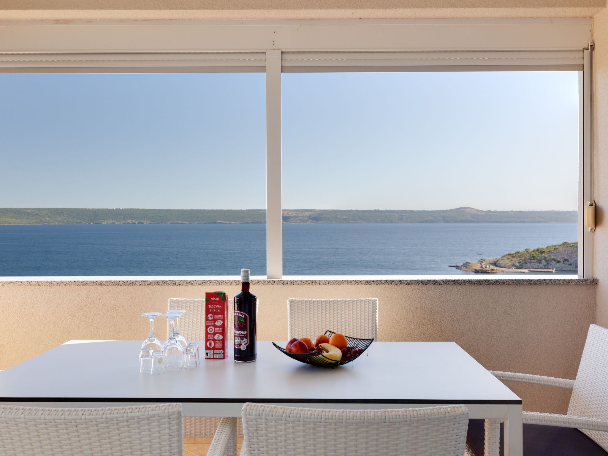 Ein Balkon mit Tisch, einer Flasche und einer Obstschale.