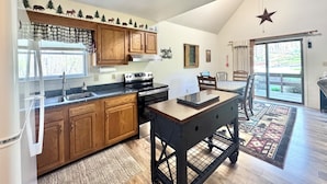 Una cocina con armarios de madera, una estufa y un comedor con mesa y sillas.