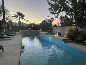 Une piscine dotée de chaises longues et agrémentée d’une cascade.