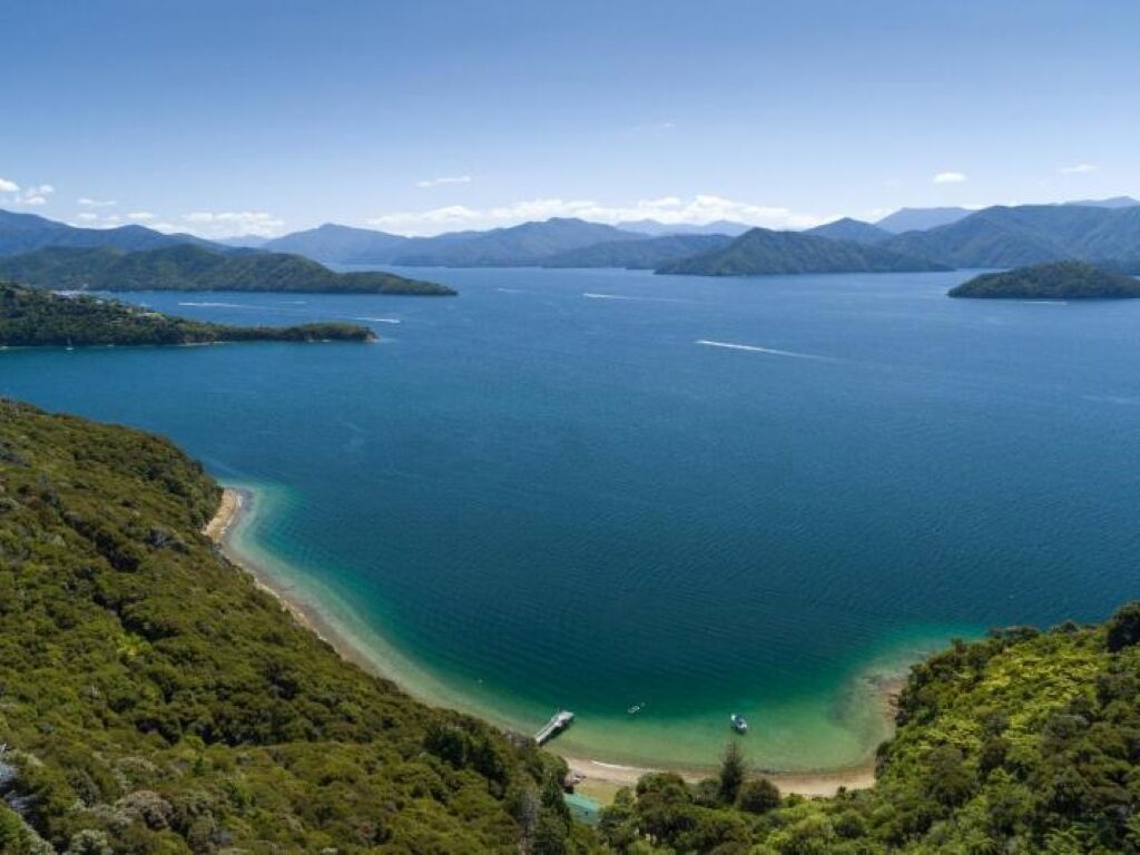 A coastal landscape with a large body of water, surrounded by hills and mountains.