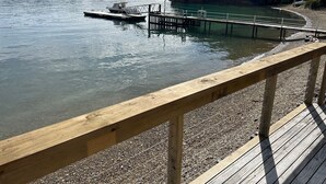 A wooden dock extending into a calm lake with a boat moored at the end.