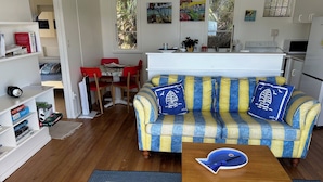 A cozy living room with a striped sofa, a wooden coffee table, and a bookshelf.