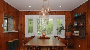 A wooden-paneled dining room with a large table, chairs, and a vase with flowers. - Blue House in Smallwood NY, Year round, 2-bed in Catskill Mts (Monticello)