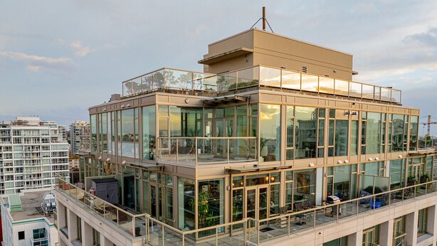 Een meerlaags gebouw met een glazen gevel, balkons en een terras op het dak.