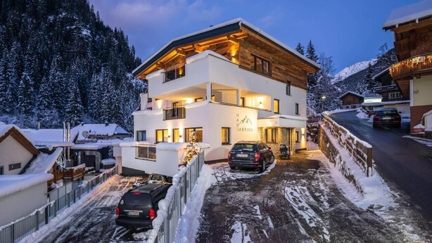 Ein modernes Hotel mit zwei Etagen und Blick auf eine Skipiste, einem überdachten Außenbereich und einem Parkplatz.