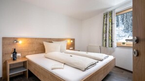 Ein Doppelbett mit Holz Kopfteil, Nachttische, ein Fenster mit Vorhängen und ein Heizkörper.