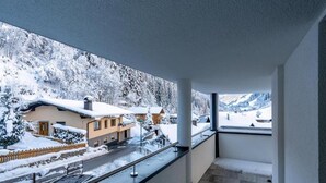 Ein Balkon mit Blick auf ein verschneites Dorf und Berge.