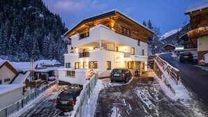 Ein modernes Hotel mit zwei Stockwerken, Blick auf eine Skipiste, einem überdachten Außenbereich und einem Parkplatz.