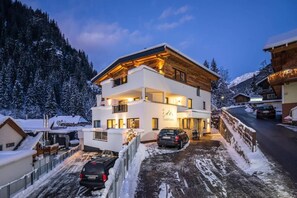 Een modern hotel met twee verdiepingen, met uitzicht op een piste, een overdekt terras en een parkeerplaats.