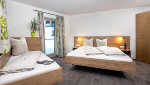 Een moderne hotelkamer met een bed, een bank, een potplant en een houten garderobe.