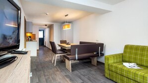 Een moderne hotelkamer met een televisie, een zithoek met een tafel en stoelen, een bank en een hanglamp.