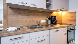 Een moderne keuken met witte kasten, een houten aanrecht, een spoelbak, een koffiezetapparaat en een oven.