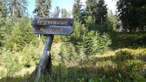 Un poste de madera con flechas indicando 'Bergrestaurant' y 'Masnerjoch'.