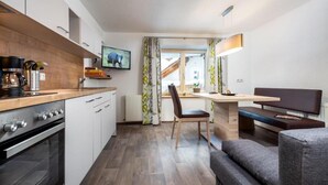 Una cocina compacta con electrodomésticos modernos, un comedor con un banco y un ventanal grande.