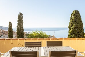 Una terraza con mesa y sillas, con vista a un cuerpo de agua y vegetación.
