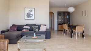 A living room with a sofa, coffee table, and dining area with chairs. - "Los Girasoles" Apartment with Sea View, Wi-Fi, and Terrace (La Herradura)