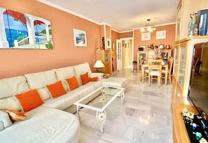A living room with a sofa, coffee table, and dining area with chairs and a table.
