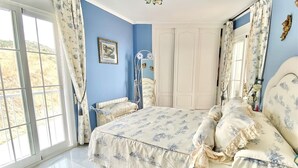 A bedroom with a large bed, a chair, a wardrobe, and a window with curtains. - "Oasis" Apartment near the Beach with Sea View, Pool, Wi-Fi, and Terrace (La Herradura)