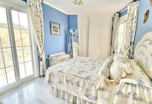 A bedroom with a large bed, a chair, a wardrobe, and a window with curtains. - "Oasis" Apartment near the Beach with Sea View, Pool, Wi-Fi, and Terrace (La Herradura)
