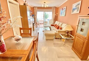 A living room with a sofa, a table with chairs, a lamp, and a vase with flowers. - Apartment "Oasis" Near the Beach with Sea View, Pool, Wi-Fi & Terrace (La Herradura)
