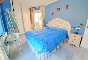 A bedroom with a bed, bedside table, lamp, and a chair.
