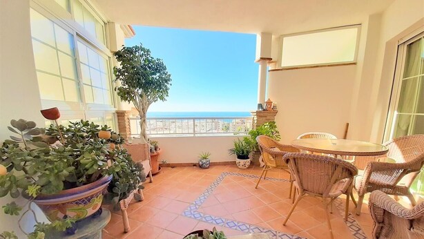A balcony with a view of the sea, wicker furniture, and potted plants. - "Oasis" Apartment near the Beach with Sea View, Pool, Wi-Fi, and Terrace (La Herradura)