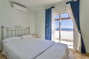 A bedroom with a bed, an air conditioning unit, a nightstand, and a view of the outdoors. - Holiday Home 'Sara' with Sea View, Wi-Fi and Air Conditioning (La Herradura)