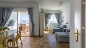 A room with a dining table, chairs, a sofa, and a view through a glass door. - Holiday Home 'Sara' with Sea View, Wi-Fi and Air Conditioning (La Herradura)