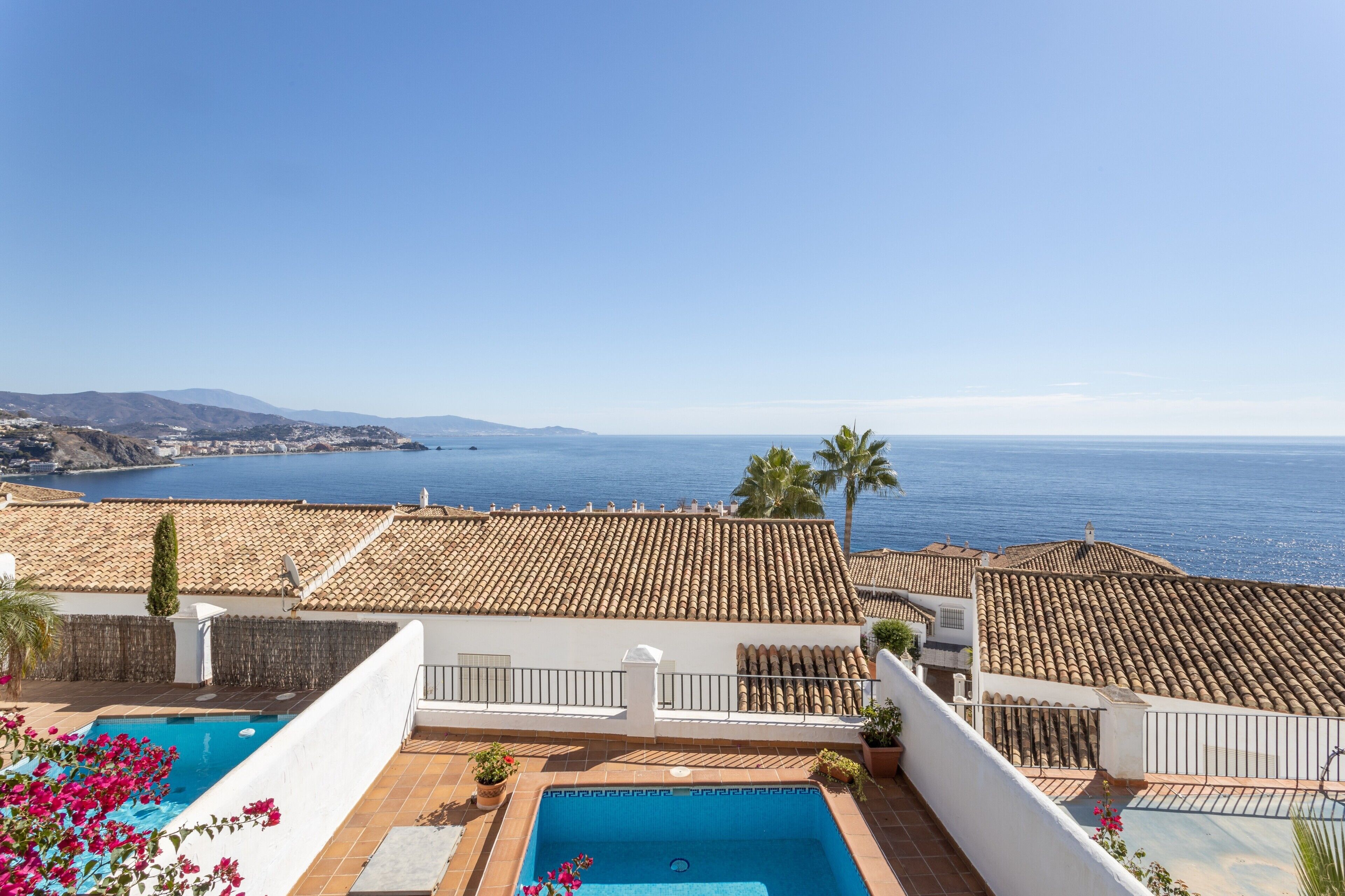 Une propriété résidentielle dotée d’une piscine, d’un toit recouvert de tuiles en terre cuite et offrant une vue sur la mer.
