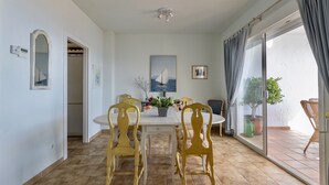 A dining area with a white table and chairs, a ceiling light, a framed picture, and a view through a glass door. - Holiday Home 'Sara' with Sea View, Wi-Fi and Air Conditioning (La Herradura)
