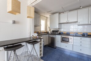 A modern kitchen with bar stools, a dishwasher, an oven, and a window.