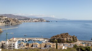 A coastal town with a marina, buildings with terracotta roofs, and a prominent rocky hill. - Apartment "Brisa de mar" Near the Beach with Sea View, Pool & Terrace (La Herradura)
