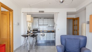 A modern kitchen with a dining area, a blue armchair, and a red chair. - Apartment "Brisa de mar" Near the Beach with Sea View, Pool & Terrace (La Herradura)