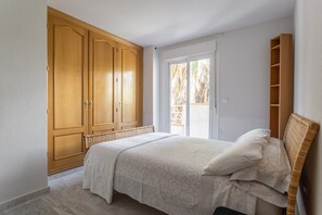 A bedroom with a bed, wooden wardrobe, and a window with a view.