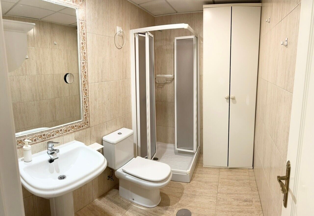 A bathroom with a sink, toilet, and shower enclosure.