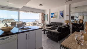 A modern kitchen with a view of the sea, a living area with a sofa, and a dining area with chairs. - Vacation Home "Vista Marina" Near the Beach with Sea View, Wi-Fi & Air Conditioning (La Herradura)