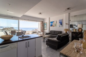 Una cocina moderna con vista al mar, una sala de estar con sofá y un comedor con sillas.