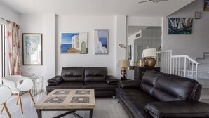 A modern living room with a dark leather sofa, a glass coffee table, and a staircase leading to an upper level. - Vacation Home "Vista Marina" Near the Beach with Sea View, Wi-Fi & Air Conditioning (La Herradura)