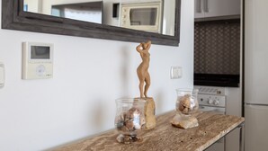 A kitchen with a microwave, oven, and refrigerator. There is a decorative wooden figure on a rock, and two glass containers with seashells. - Vacation Home "Vista Marina" Near the Beach with Sea View, Wi-Fi & Air Conditioning (La Herradura)