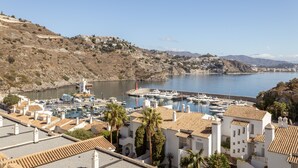 A coastal town with a marina, white buildings with terracotta roofs, and a hilly backdrop. - Vacation Home "Vista Marina" Near the Beach with Sea View, Wi-Fi & Air Conditioning (La Herradura)
